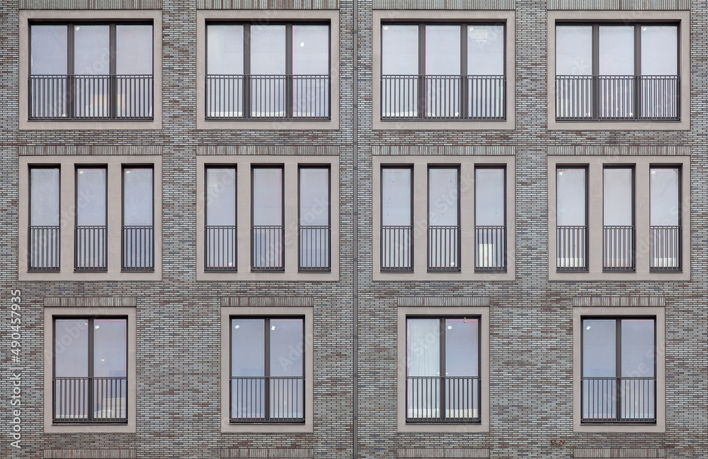 Fototapeta premium Background image - brick wall of a building with windows of different sizes