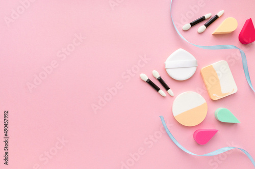 Makeup flat lay. Various foundation sponges and eyeshadow applicators on pink background, space for text