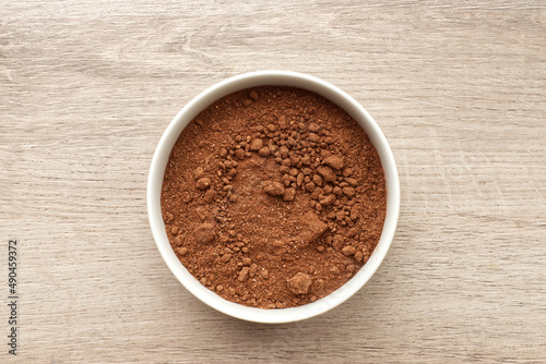 Cocoa in a bowl on wooden background. Top view.