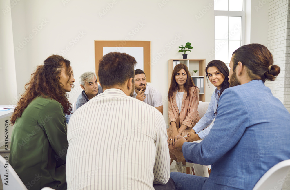 Group of people having a discussion during an informal business meeting in their office. Team of young and mature employees sitting in a circle and listening to their team leader or leadership coach Group of people having a discussion during an informal business meeting in their office. Team of young and mature employees sitting in a circle and listening to their team leader or leadership coach