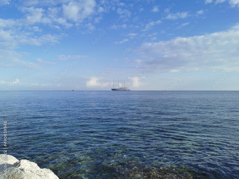 The largest sailing yacht in the world, an eight-deck motorsailer on the Mediterranean coast against a blue sky with clouds.