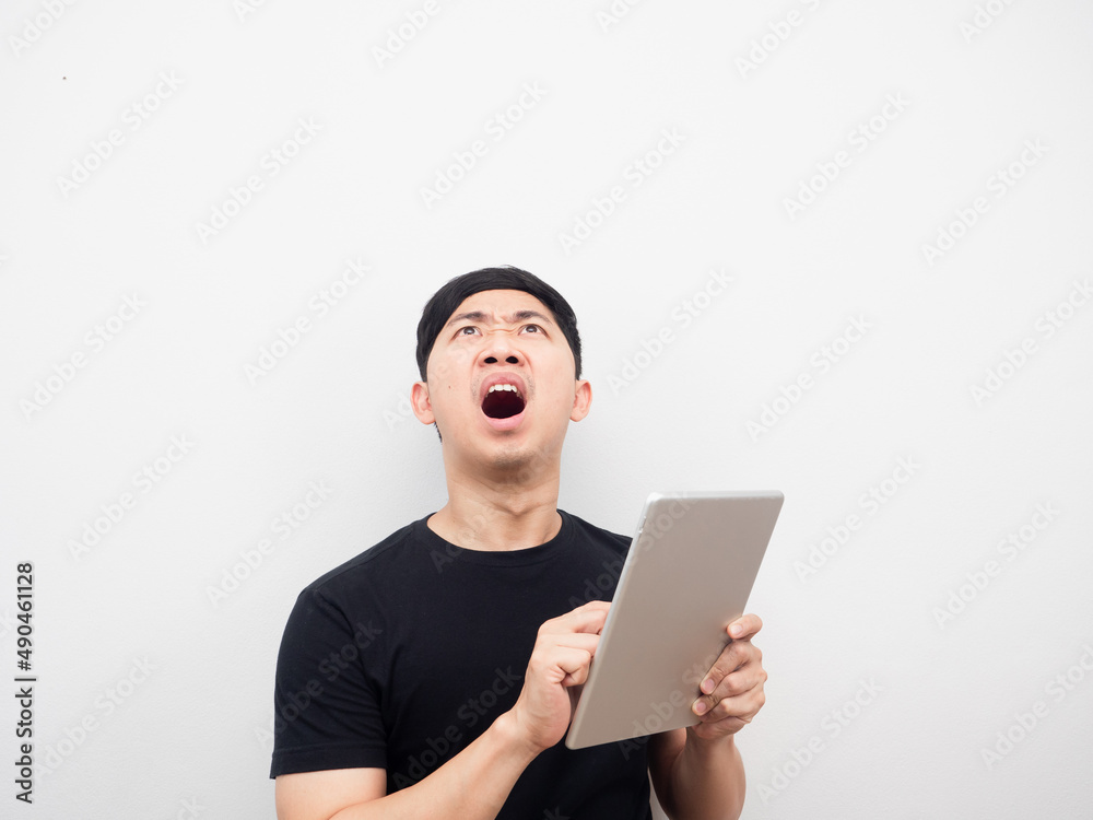 Man using tablet feeling shocked and looking above copy space Man using tablet feeling shocked and looking above copy space