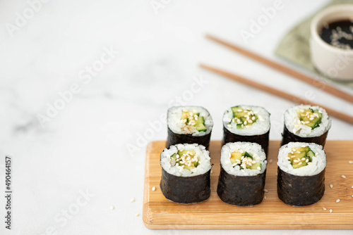 vegetable sushi with cucumber and sesame seeds on a wooden board photo