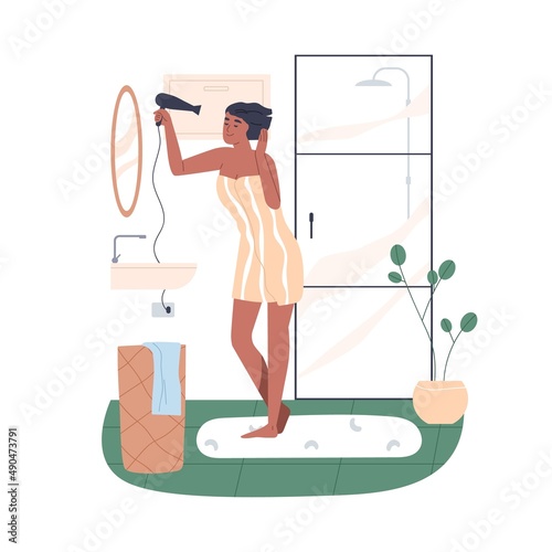Woman drying wet hair with blowing hairdryer in front of mirror in bathroom. ...