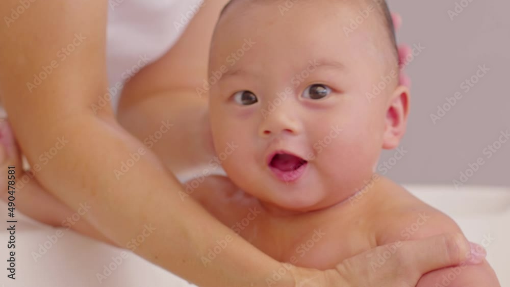 Calm of asian newborn baby bathing in bathtub.mother bathing her son in warm water.Happy adorable newborn infant smile in tub relax and comfortable.Newborn baby care concept Calm of asian newborn baby bathing in bathtub.mother bathing her son in warm water.Happy adorable newborn infant smile in tub relax and comfortable.Newborn baby care concept