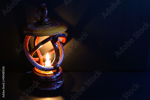 The candle in the lamp shines in the darkness.