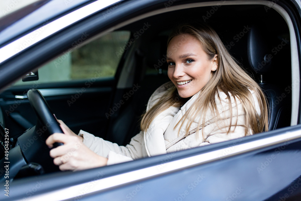 Young woman driver sitting in car, driving in the street