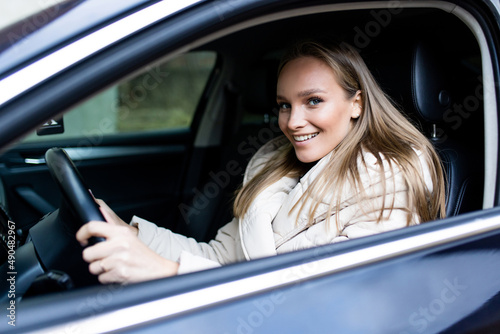 Young woman driver sitting in car, driving in the street