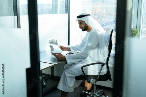 Photography handsome man with dish dasha working in his business office of Dubai