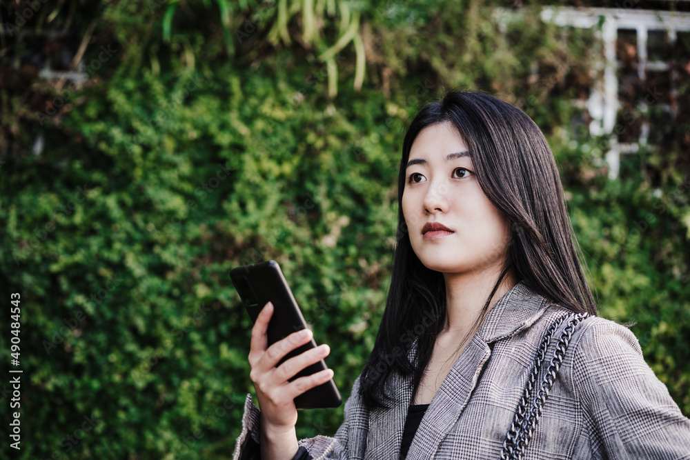 portrait of beautiful chinese business woman using mobile phone in building office. Technology