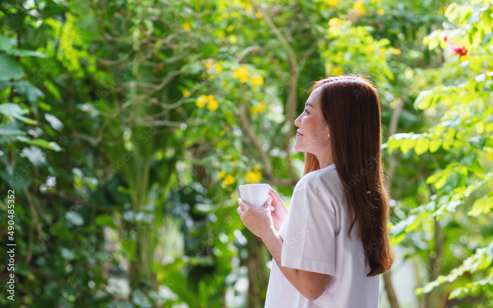 Portrait image of a beautiful young asian woman drinking coffee and relaxing with nature views Portrait image of a beautiful young asian woman drinking coffee and relaxing with nature views