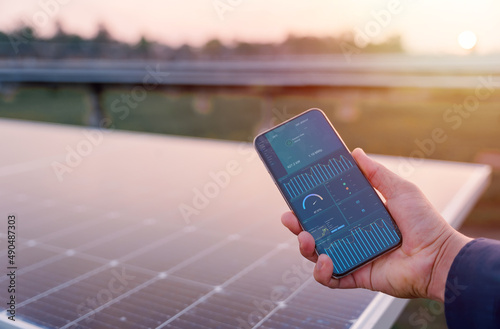 Man hand holding the telephone for monitoring performance in solar power plant(solar cell). Alternative energy to conserve the world\'s energy, Photovoltaic module idea for clean energy production