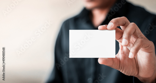 Businessman ,Business Man's hand hold showing business card - close up shot on grey background. Show a blank piece of paper. Paper visit card.