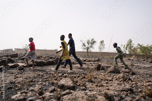 Slika na platnu Group of young black African kids crossing a stony infertile field in the Sahel