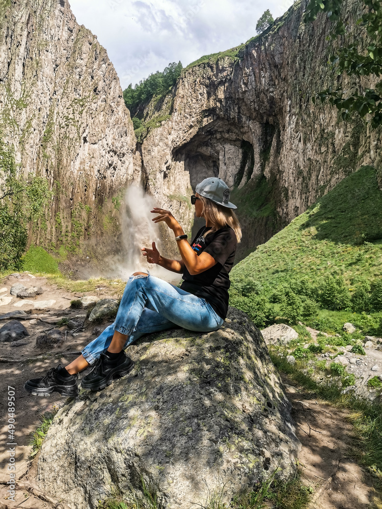 A girl on the background of the Tuzluk-Shapa waterfall on the territory of Kabardino-Balkaria. Caucasus. Russia. A girl on the background of the Tuzluk-Shapa waterfall on the territory of Kabardino-Balkaria. Caucasus. Russia.