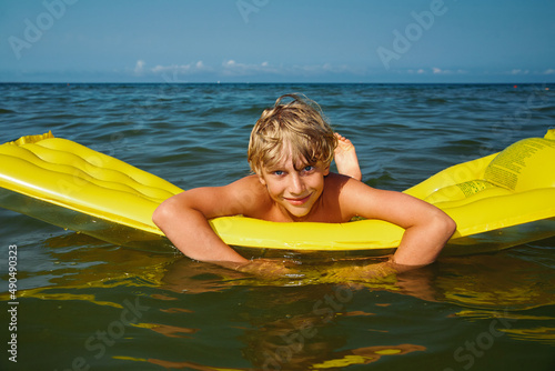 Teen boy swimming on air mattress in the sea and enjoying summer vacation