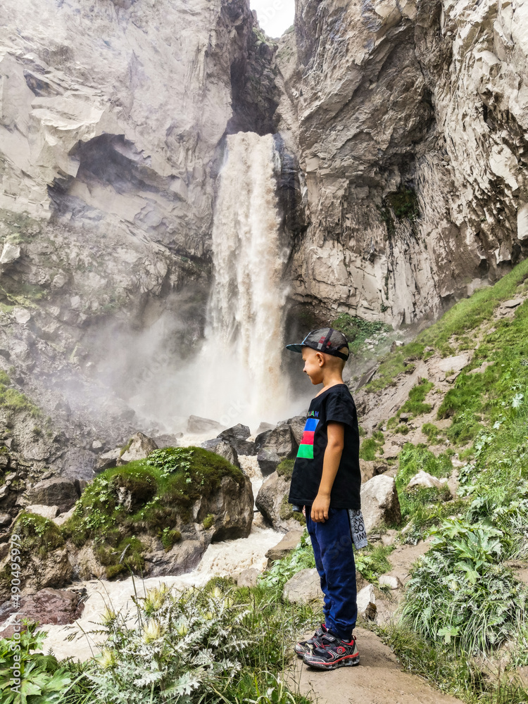 A boy at the Sultan-su waterfall surrounded by the Caucasus Mountains near Elbrus, Jily-su, Russia