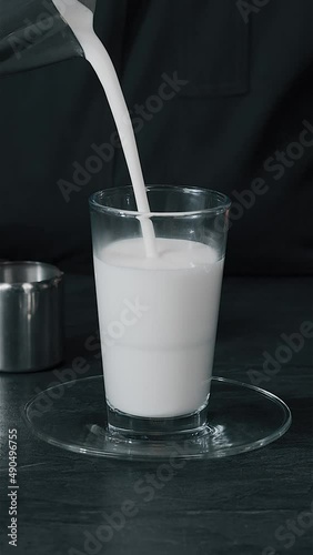 Barista pouring milk in hot coffee and making cappuccino foam in cafe close up,