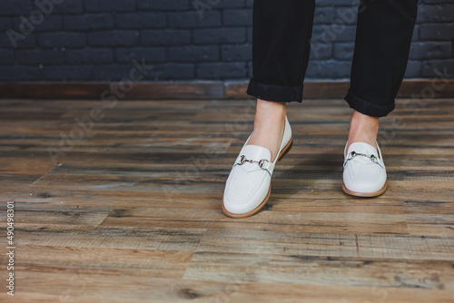 Close-up female legs in black trousers and leather beige moccasins. New spring-summer collection of women's leather shoes 2022