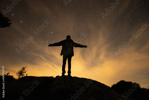Silhouette of man under beautiful orange lights with starry sky at night in Sweden