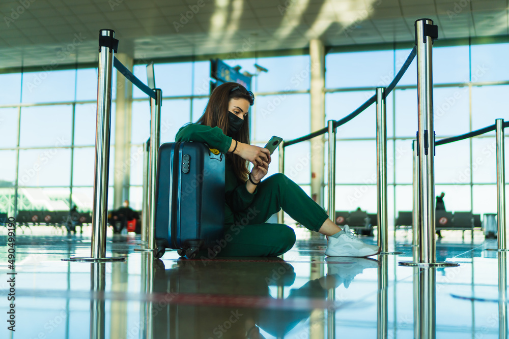 Woman sitting on the airport floor with her suitcase