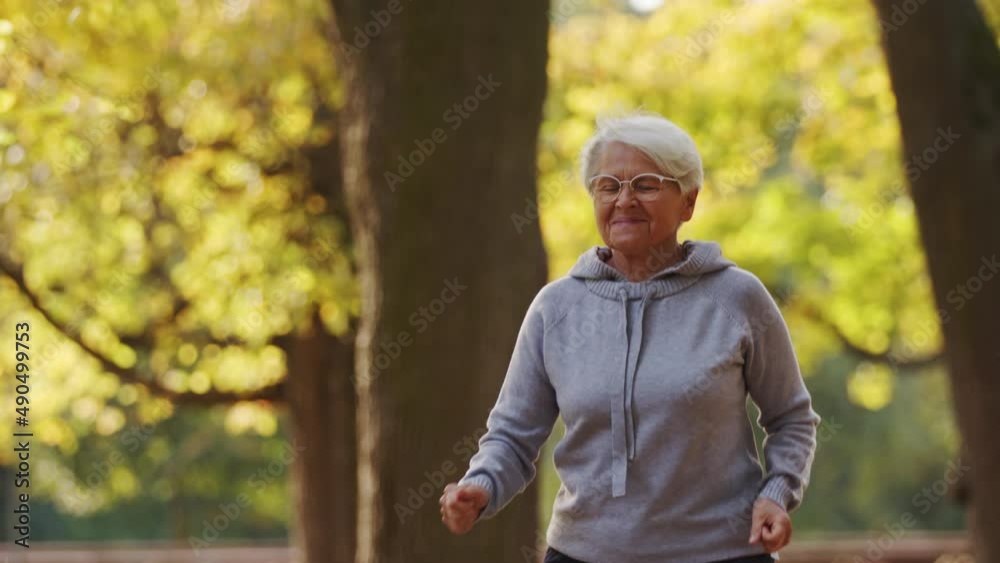 Retired elderly caucasian woman bravely jogging in the public park, trying to keep her body fit. High quality 4k footage Retired elderly caucasian woman bravely jogging in the public park, trying to keep her body fit. High quality 4k footage