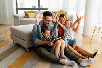 Happy young family having fun time at home. Parents with children using tablet