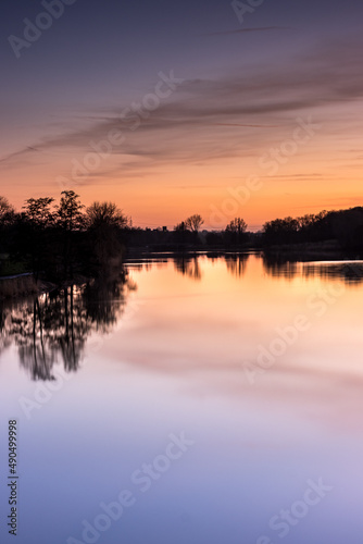 Purple, orange and yellow sky at sunset at Aasee in Münster with reflection in water.