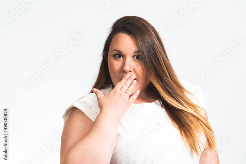 portrait of a chubby young woman with her hand covering her mouth.