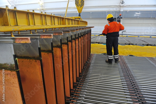 East Kazakhstan region, Kazakhstan - 12.02.2015 : A worker washes plates with cathode copper at an industrial plant photo