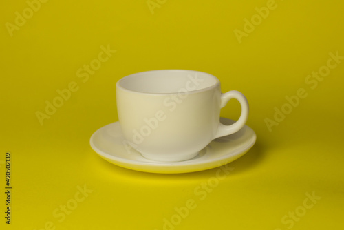 white cup with saucer on a yellow background