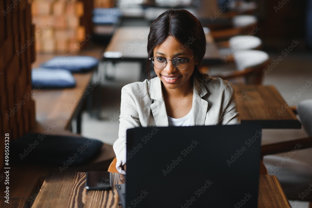 Young beautiful Afro-American businesswoman using laptop while working in cafe