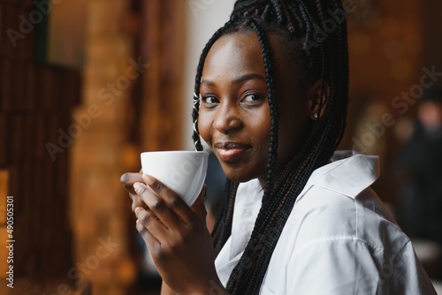Young african woman at cafe drinking coffee.