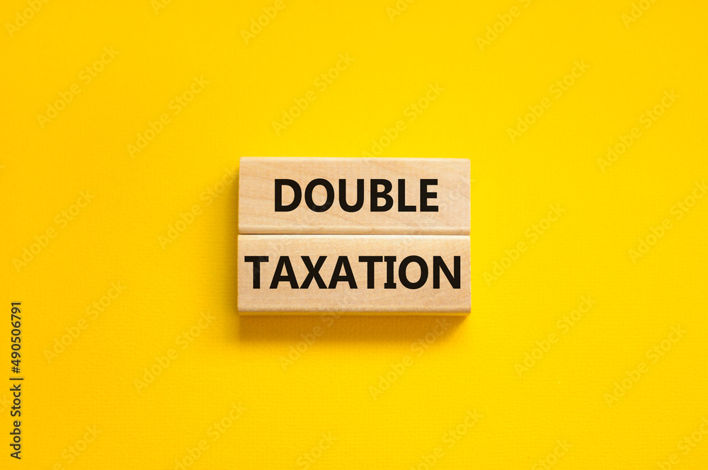 Double taxation symbol. Concept words Double taxation on wooden blocks on a beautiful yellow table yellow background. Business tax and double taxation concept, copy space. Double taxation symbol. Concept words Double taxation on wooden blocks on a beautiful yellow table yellow background. Business tax and double taxation concept, copy space.