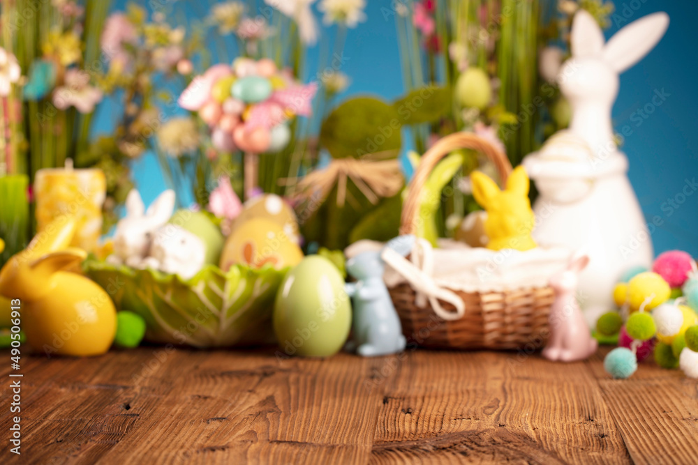 Easter time. Easter decorations on the rustic wooden table. Easter bunny, easter eggs in basket and cabbage leaf. Bouquets of spring flowers. 