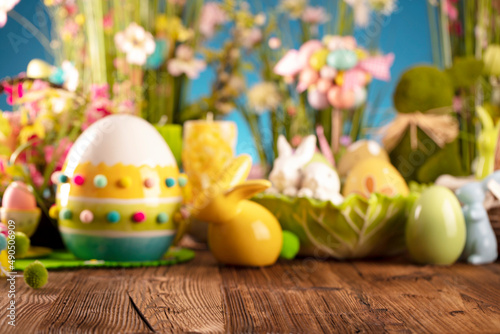 Easter time. Easter decorations on the rustic wooden table. Easter bunny, easter eggs in basket and cabbage leaf. Bouquets of spring flowers. 