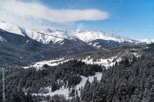 Sunny day in Arkhyz ski resort. Winter mountains and forest. 