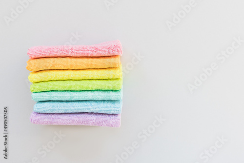 New folded microfiber cloth for cleaning in seven rainbow colors on gray background. Cleaning micro fabric towels for dusting and polishing. Domestic household cleaning service concept. Top view, copy