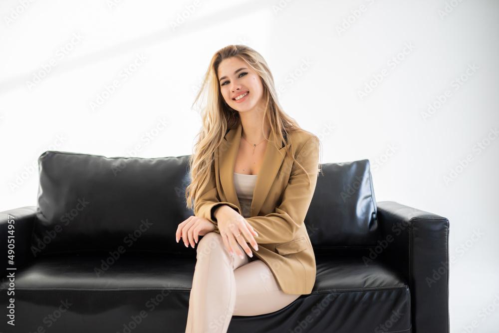 Young pretty woman sitting on a sofa and looking in the camera isolated on white background Young pretty woman sitting on a sofa and looking in the camera isolated on white background