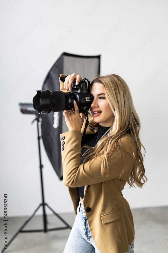 Young beautiful female posing for a photo shoot in a studio, a photographer is shooting with a digital camera - obrazy, fototapety, plakaty 