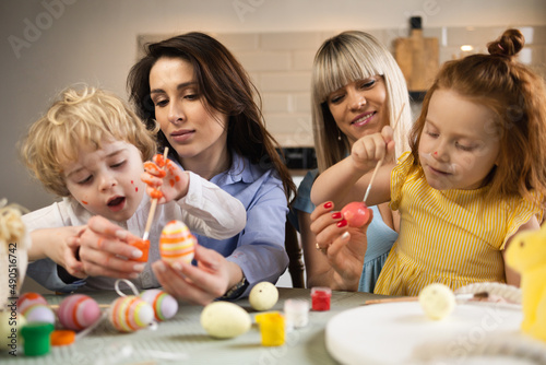 Two mothers with their children color eggs in preparation for Easter