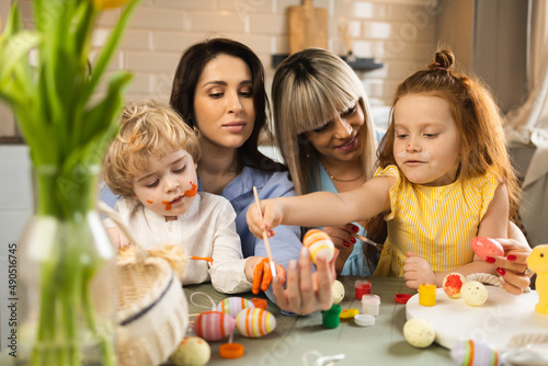Happy mothers and their children decorating Easter eggs