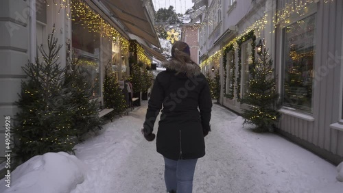 Woman Walking Around Kragero Winter Town, Shops Illuminated With Christmas Lights Decorations - wide shot photo