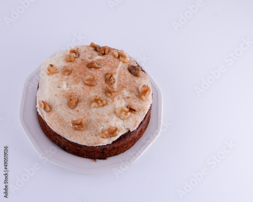 Traditional Carrot Cake with cream cheese frosting and walnuts on plate isolated on left side white background
