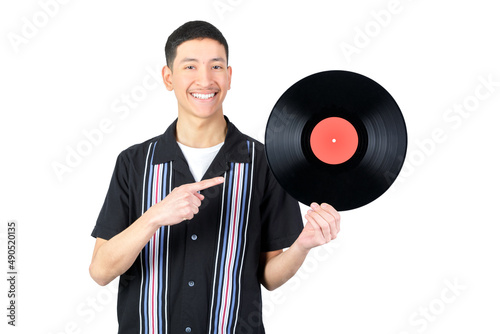 Happy guy holding a vinyl record and pointig it. Smiling looking at camera. Isolated on white background. 18-20 years old latin american guy. photo