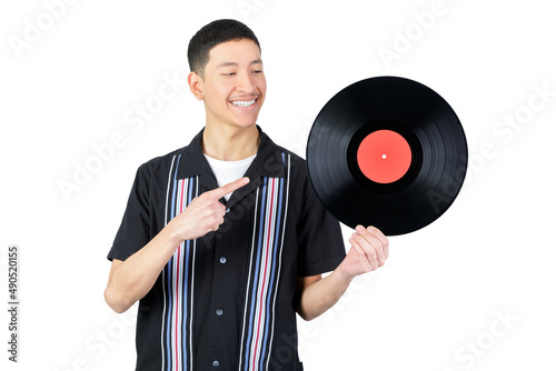 Happy guy holding a vinyl record and pointig it. Isolated on white background. 18-20 years old latin american guy. photo