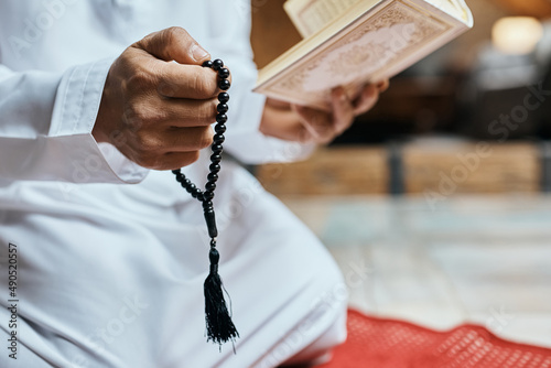 Canvas Print Close-up of Muslim man uses misbaha beads while reading from Koran at home