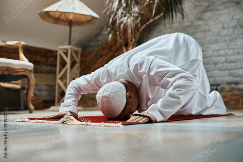 Religious Muslim man prostrating to God while praying at home. photo
