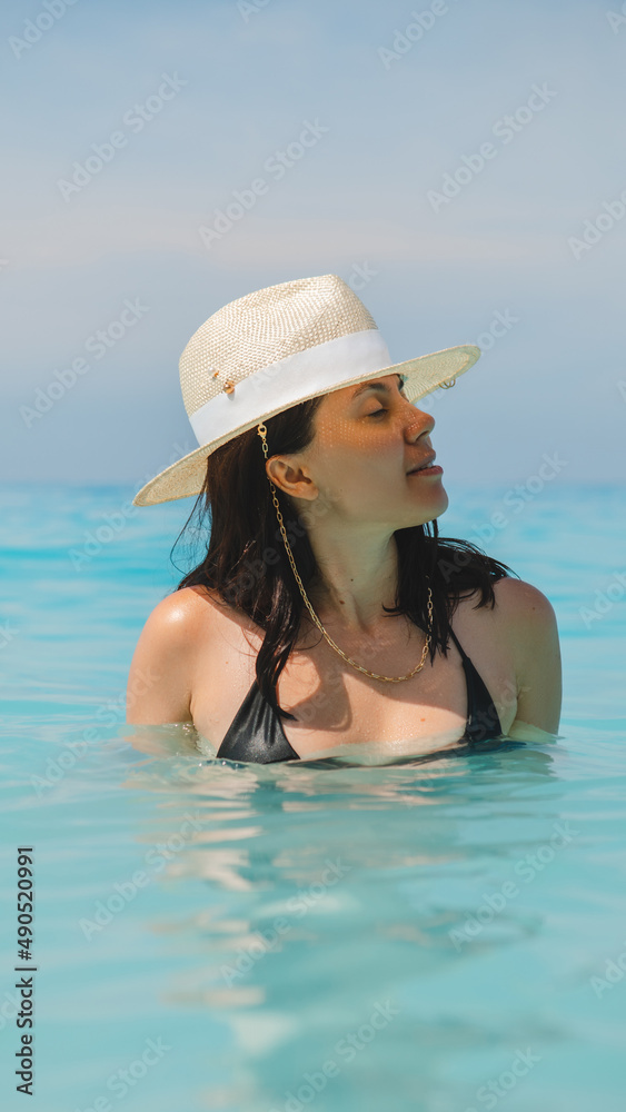 woman in white hat and black swimsuit in blue sea water