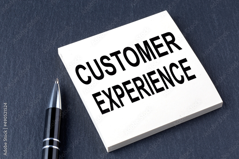 CUSTOMER EXPERIENCE text on the sticker with pen on the black background CUSTOMER EXPERIENCE text on the sticker with pen on the black background